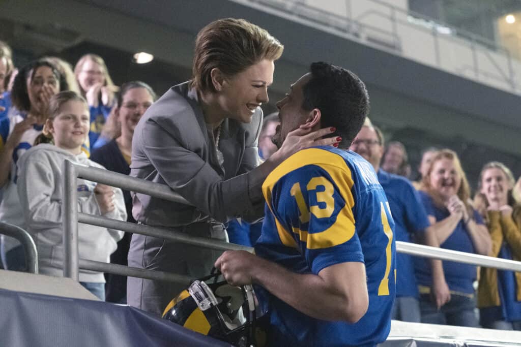 Zachary Levi in a football uniform and Anna Paquin in the football stands
