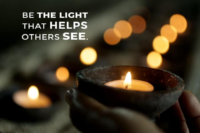 Be the light that helps others see hands holding a candle with other small candles in the background