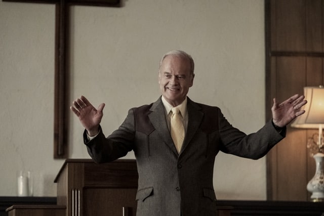 Kelsey Grammer playing Chuck Smith standing with his hands out.