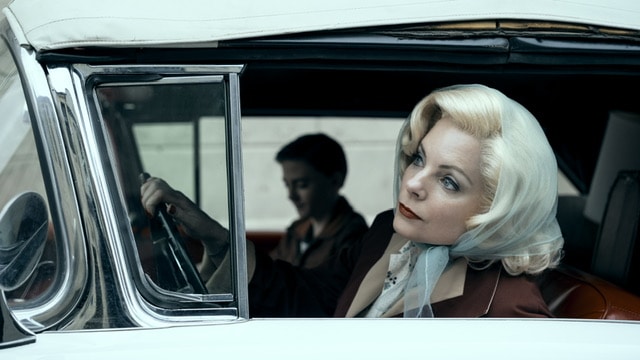 Marilyn Monroe looking woman sitting in a car.