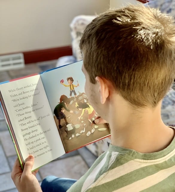 Boy reading chapter book The Boxcar Children with wonderful illustrations