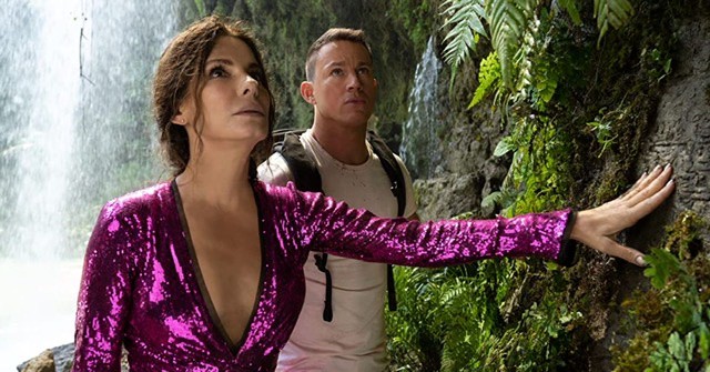 Loretta sage and Dash in the jungle next to a waterfall in The Lost City