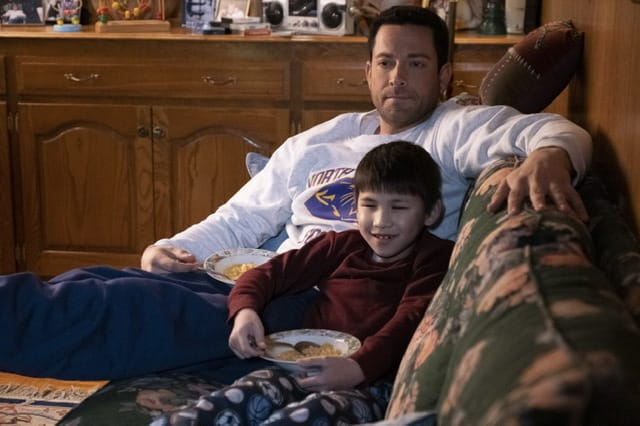 Man and boy on couch watching television