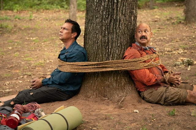 Two men tied with a rope to a tree