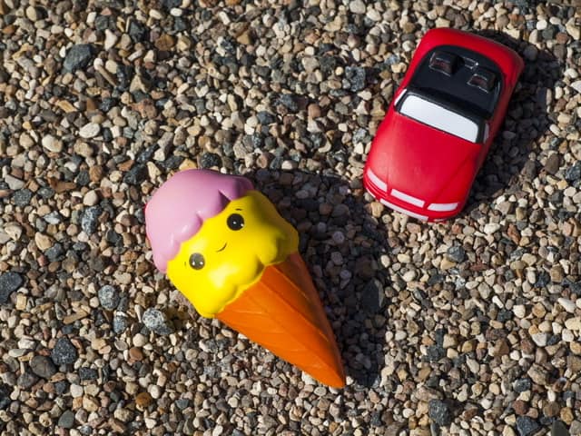 Two squishies sitting on the ground. One ice cream cone and one red convertible car