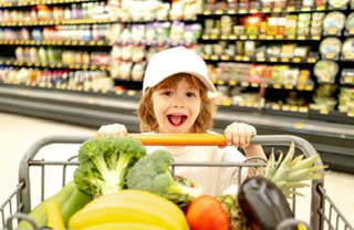 Child with grocery cart full of vegetables