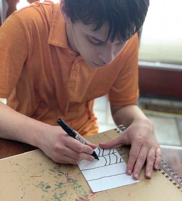 Boy drawing lines on art paper