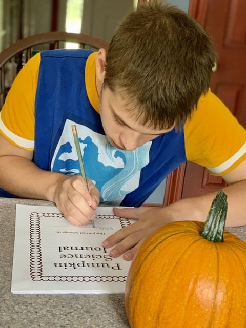Boy working on pumpkin science unit in homeschool