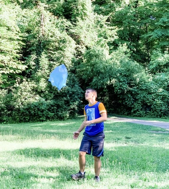 Boy Playing outside with a plastic bag parachute. Fun Experiments for Science