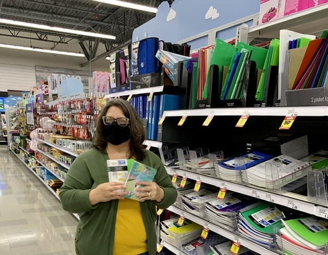 woman with mask holding notebooks in Meijers