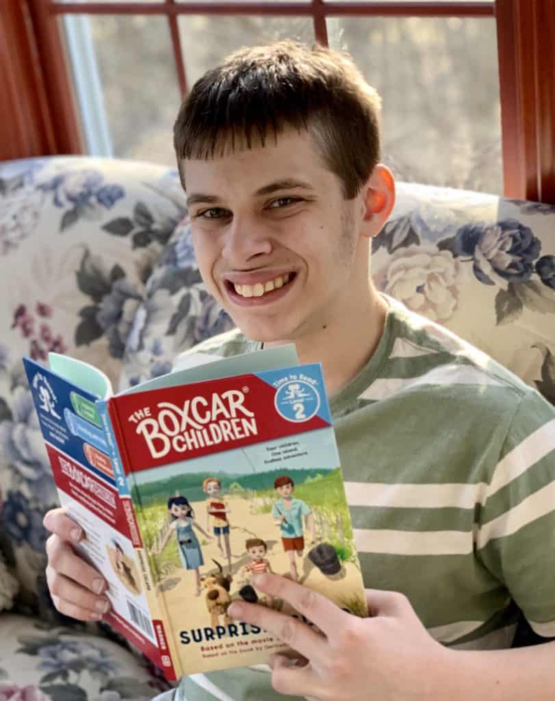 Boy smiling with The Boxcar Children Surprise Island Time to Read Level 2