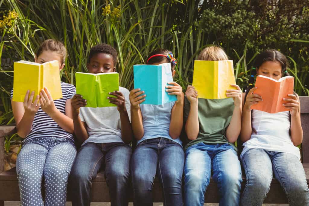 Five children readings books with the books covering their faces