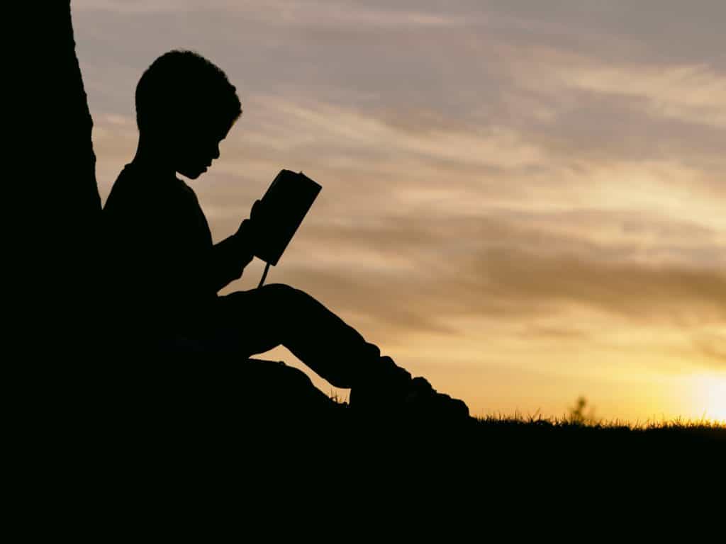 Child reading outside at sunset