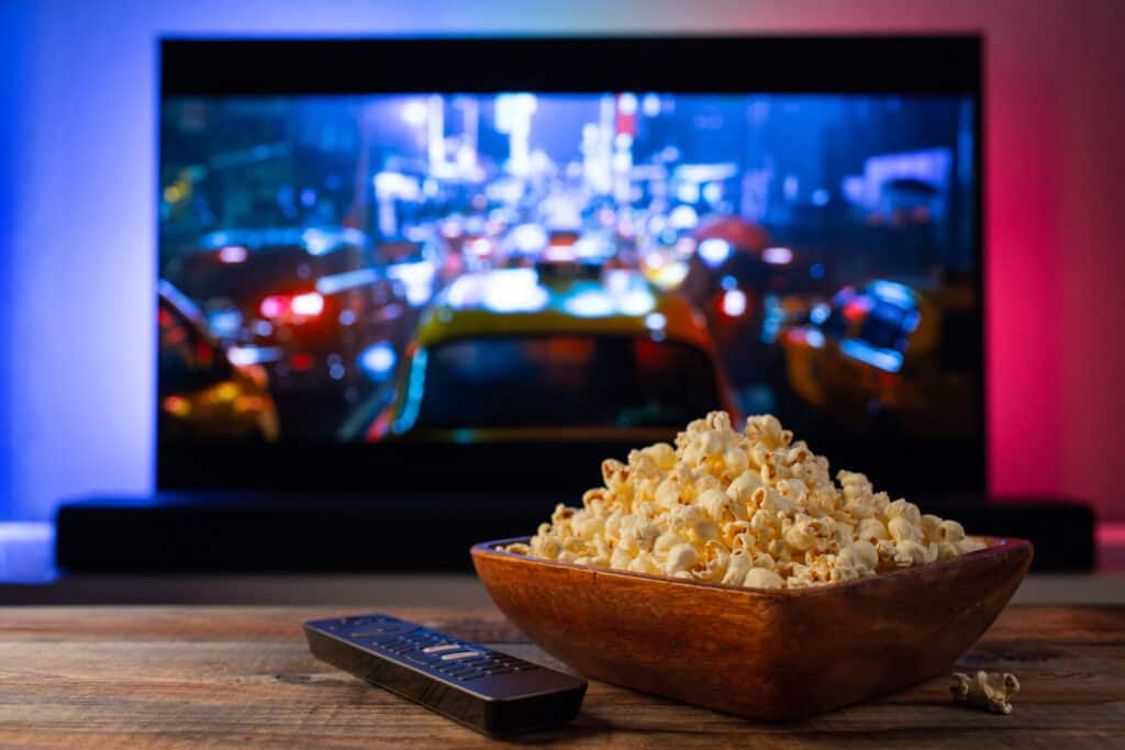 Bowl of popcorn on a table with the television in the background