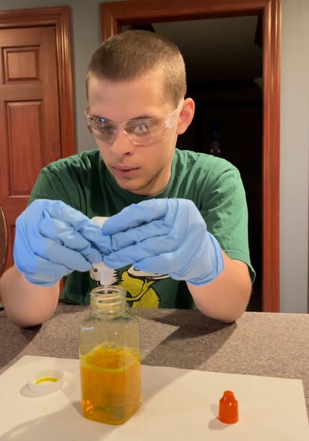 White teenage male with blue latex gloves on conducting a science experiment
