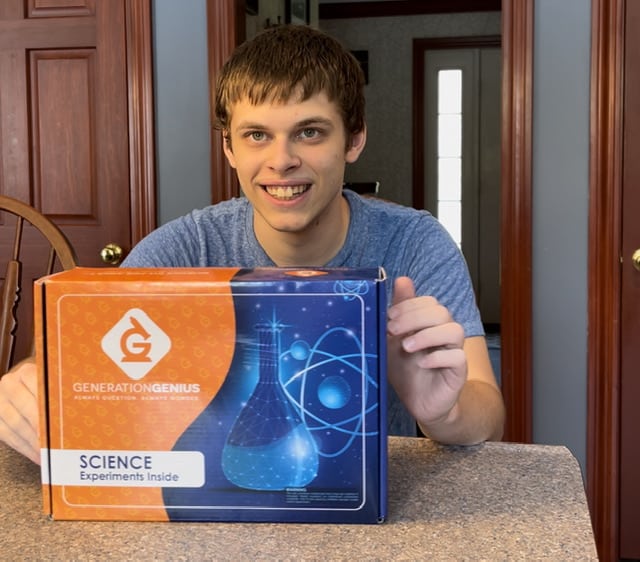 white male teen holding a science kit from Genration Genius