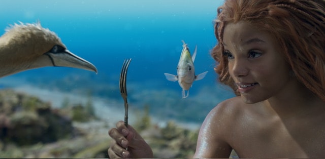 Teen black girl underwater holding a fork with a fish and a bird watching.
