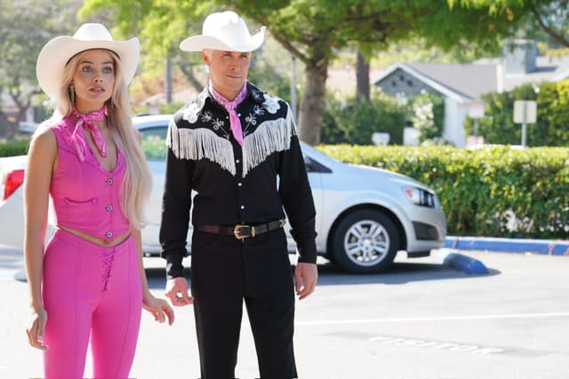 Barbie dressed in pink pants and a pink vest with a white cowboy hat. She has a pink bandana around her neck. Ken has black pants and a black cowboy shirt with white fringe. He also has on a white cowboy hat and a pink bandana.