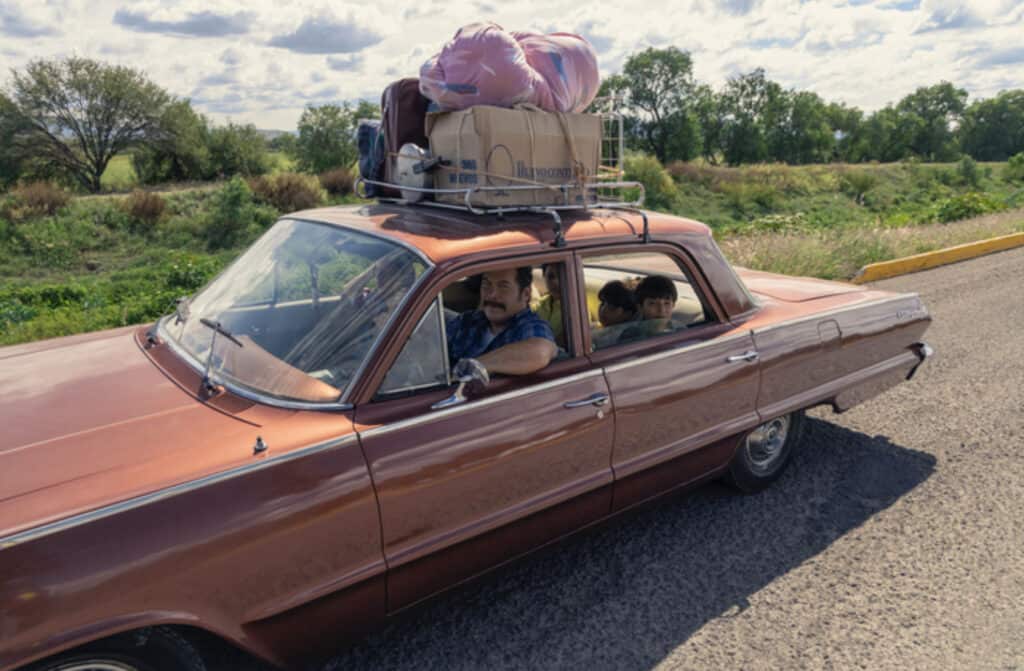 Car with migrant farmerworkers. Their belongings are strapped to the roof of the car.