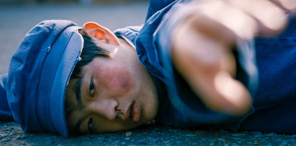 A Chinese boy laying on the ground after being beaten