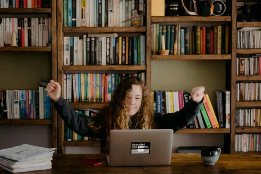 girl on computer in front of bookshelves