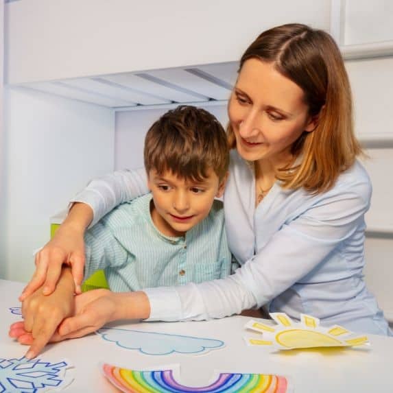 White woman helping a young white boy with lesson.