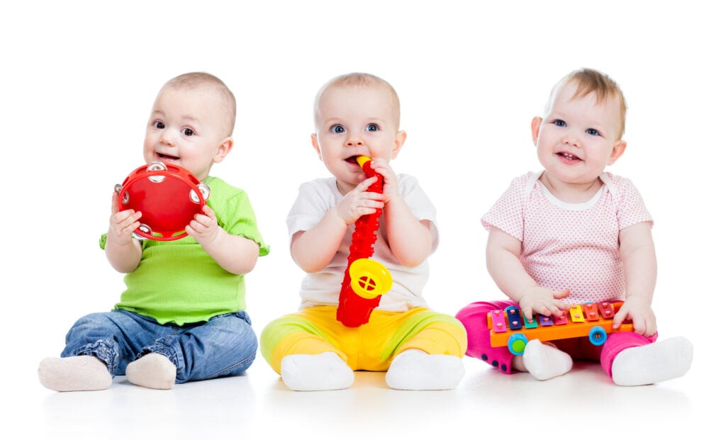 Three toddlers playing with toy instruments