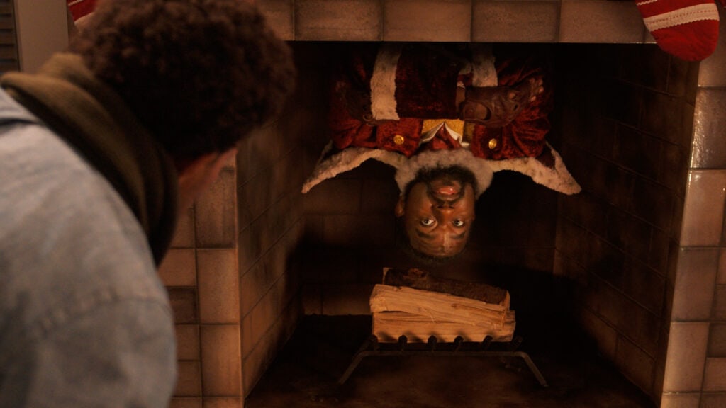 Lil Rel Howery as Nick hanging upside down from the inside of a chimney.