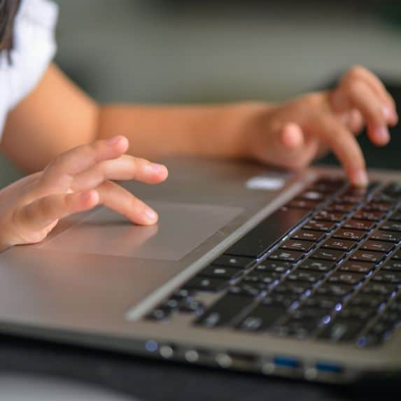 child typing on a keyboard